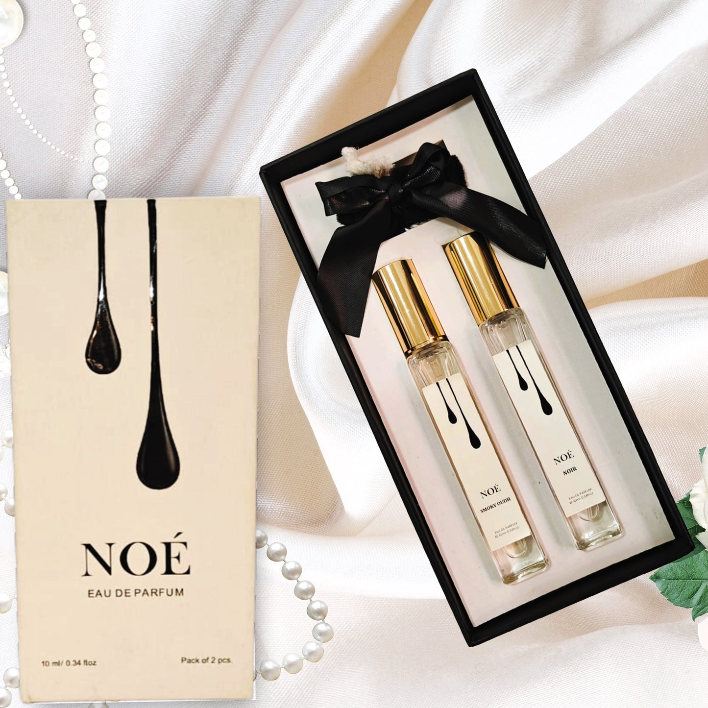 NOÉ Eau de Parfum gift set with two 10ml spray bottles on white satin background