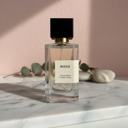Rouge Eau de Parfum 100ml glass bottle on marble surface with soft pink wall and greenery background